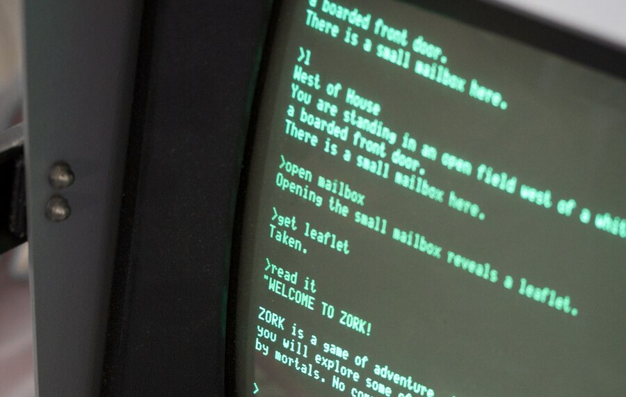 Zork gameplay on a CRT terminal: West of House, opening the mailbox, and the Welcome to Zork message